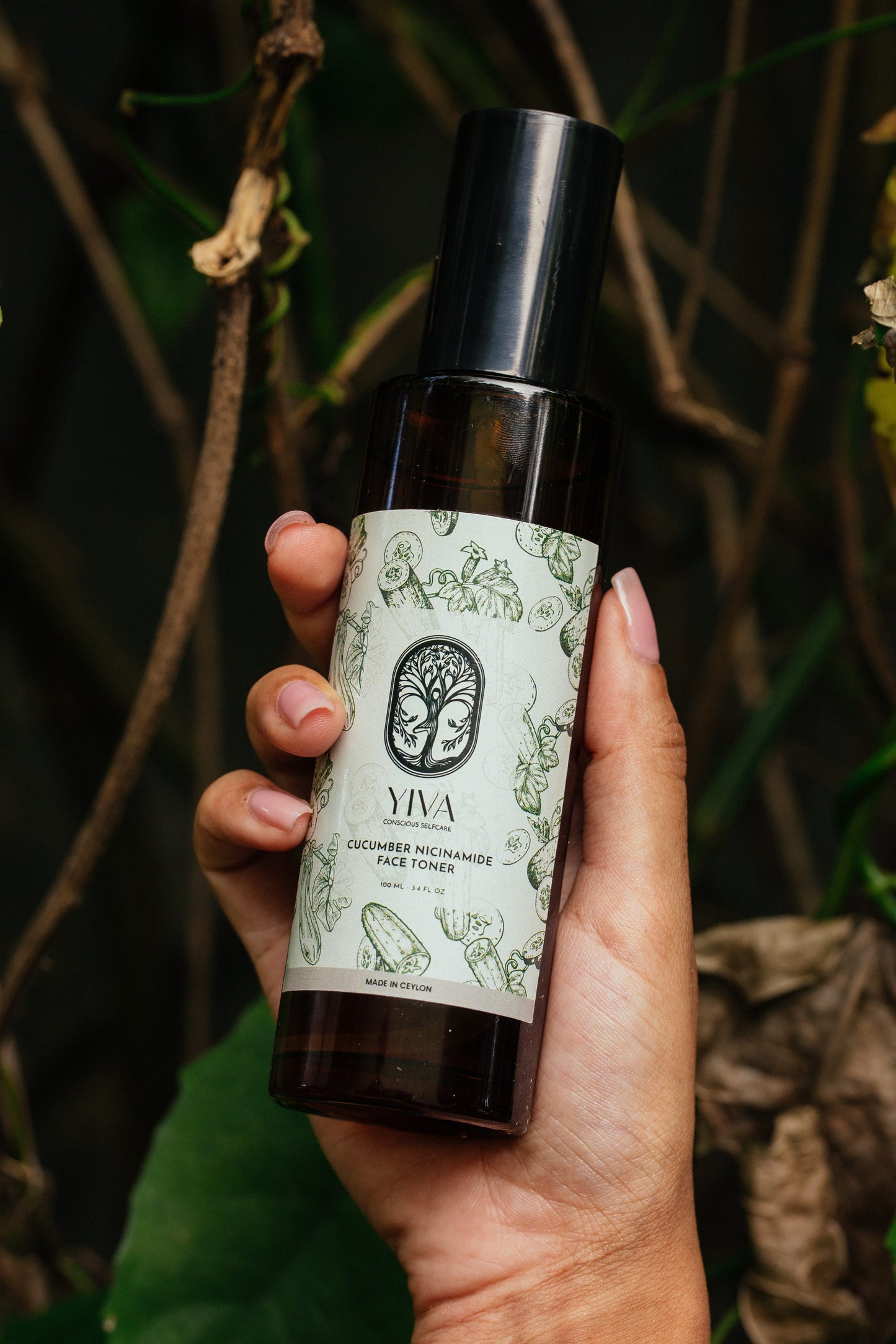 Hand holding a bottle of YIVA skincare product with a natural background