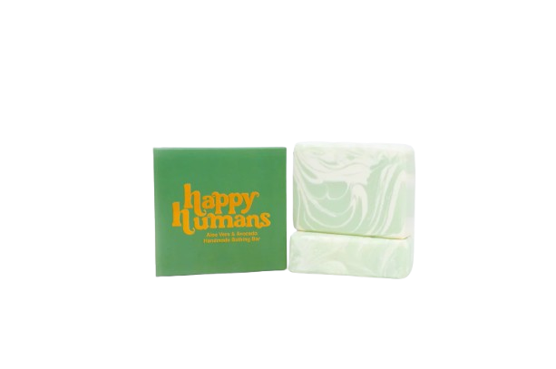 Gift set from HappyHumans including a green aloe vera and green tea bathing bar, a berry lip balm, and a vanilla body oil, all packaged in a matching green box with gold accents.