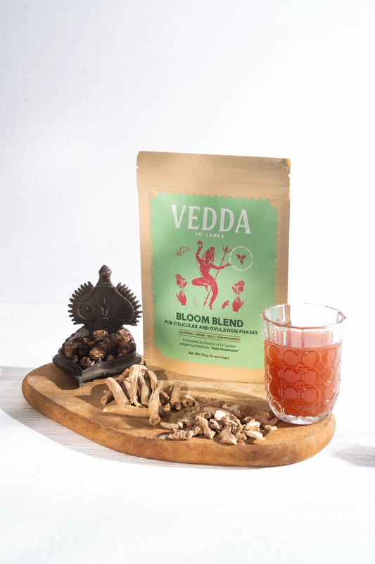 Vedda Bloom Blend tea package on a wooden tray with a glass of tea and snacks.
