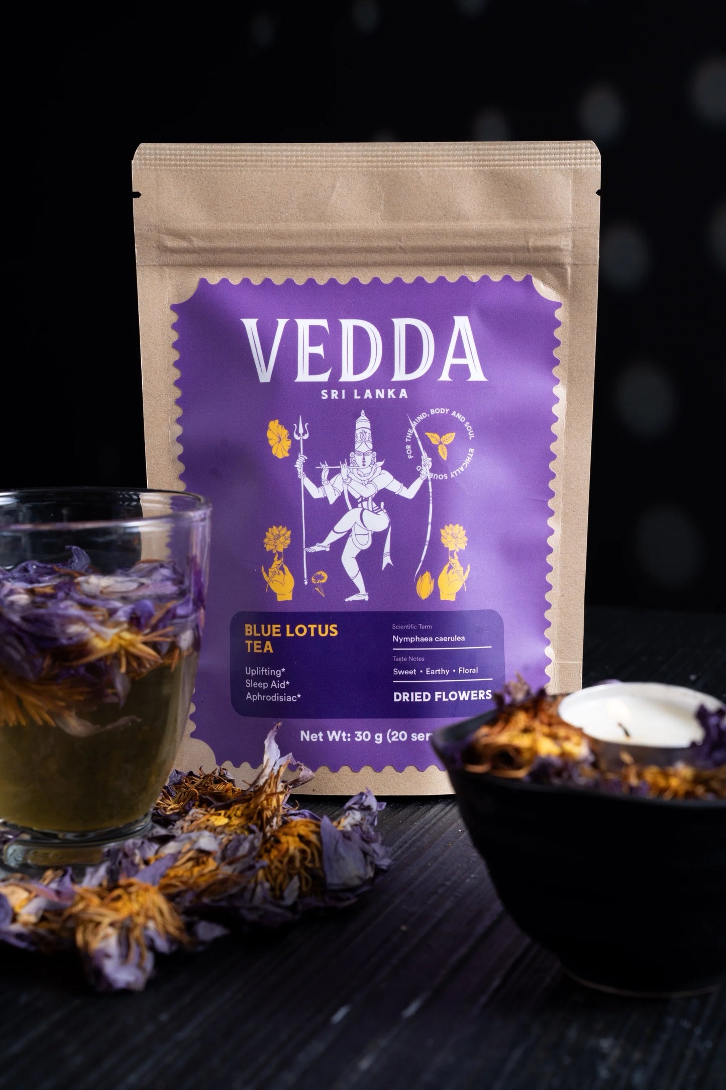 Vedda Sri Lanka Blue Lotus Tea package with a cup of tea and dried flowers on a dark background