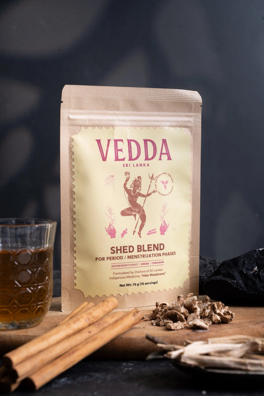 Vedda Shed Blend package with a glass of tea and cinnamon sticks on a dark background.