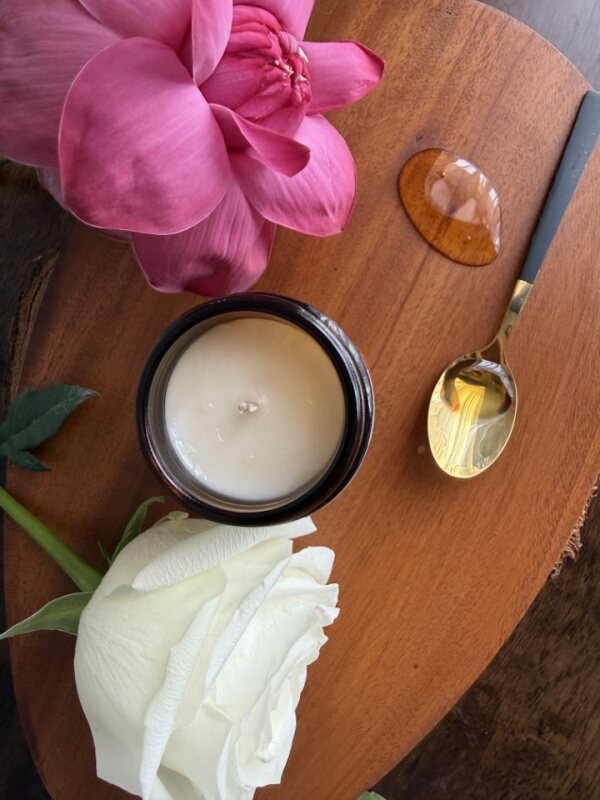 Candle, pink flower, white rose, and spoon on a wooden surface