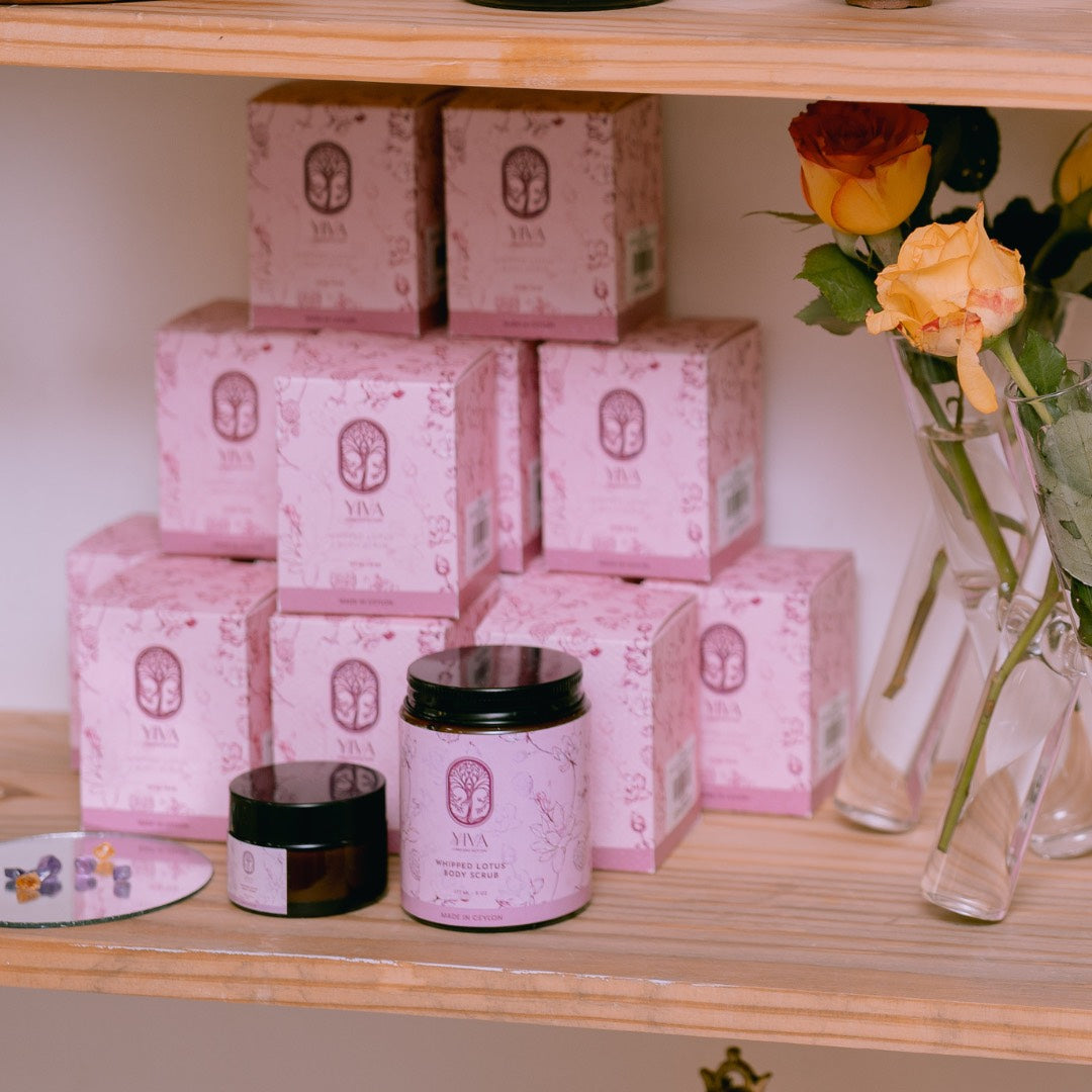 Pink boxes and jars on a wooden shelf with flowers in the background