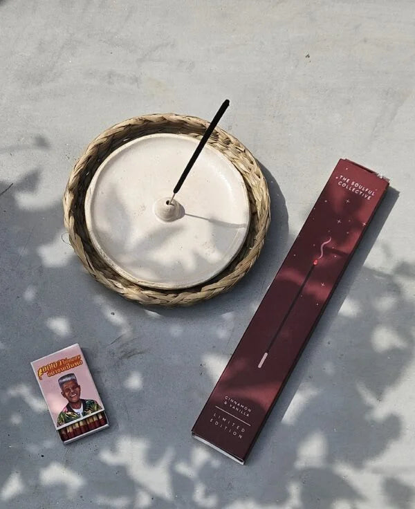 Incense stick, woven holder, and packaging on a light surface